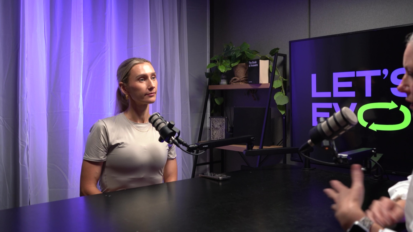 A podcast guest against the studio's coloured backdrop